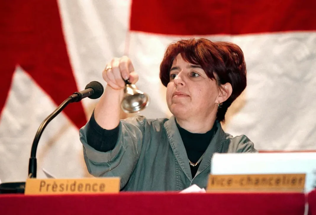 SUISSE : Elisabeth Baume-Schneider tire à boulets rouges sur les algériens, et se fait dézinguer. Elisabeth Baume-Schneider agitant une cloche lors d'une réunion officielle.