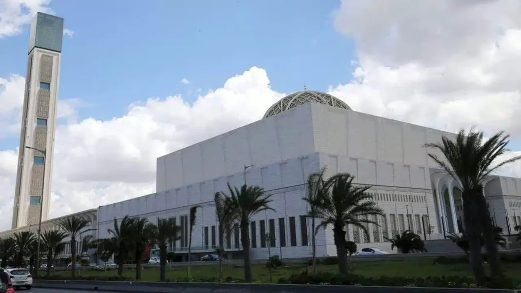 Ce touriste marocain tombe d’admiration pour la grande mosquée d’Alger. Vue extérieure de la grande mosquée d'Alger avec palmiers et ciel nuageux.