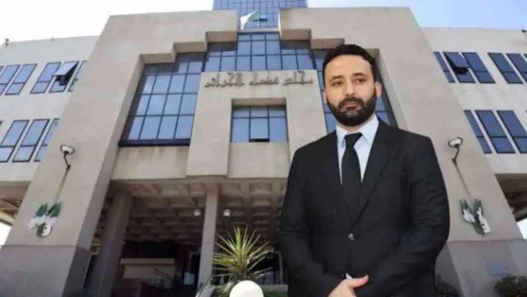 Affaire ALRIM : l’ancien ministre délégué Nassim Diafat est toujours en prison Nassim Diafat en costume devant un bâtiment officiel en Algérie.