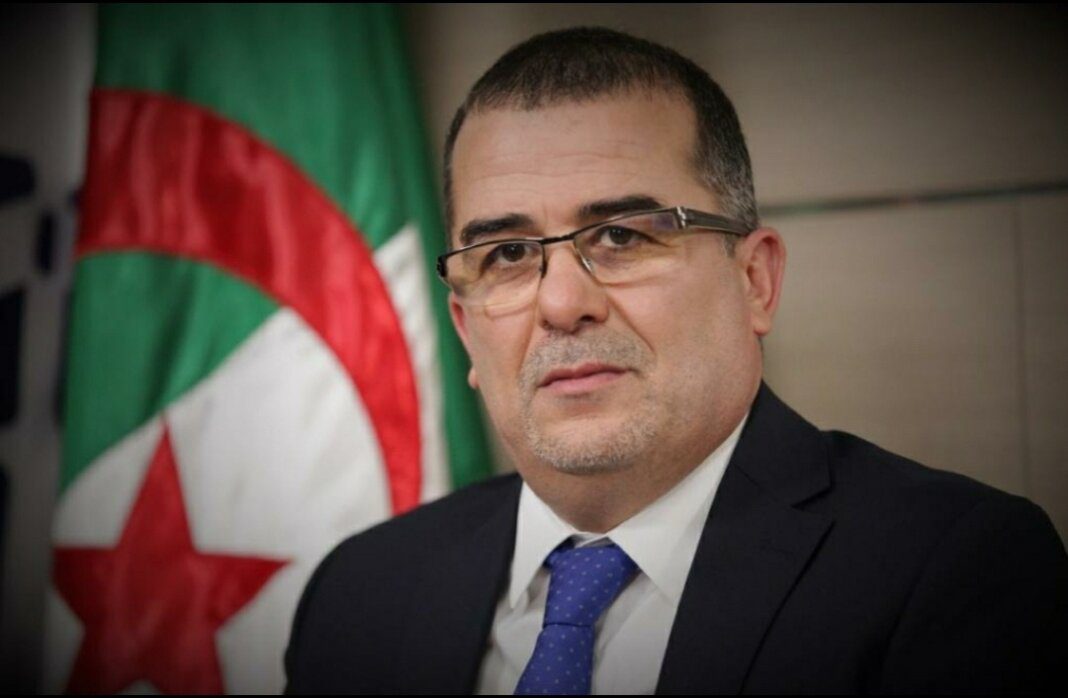 Le ministre du Travail présente le projet de loi sur le droit de grève Homme politique en costume avec drapeau algérien en arrière-plan.