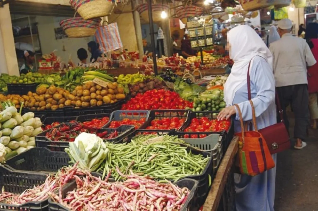 Algérie : les prix des produits de premières nécessités ont terriblement augmenté Vendeuse dans un marché algérien avec étalage de fruits et légumes frais.