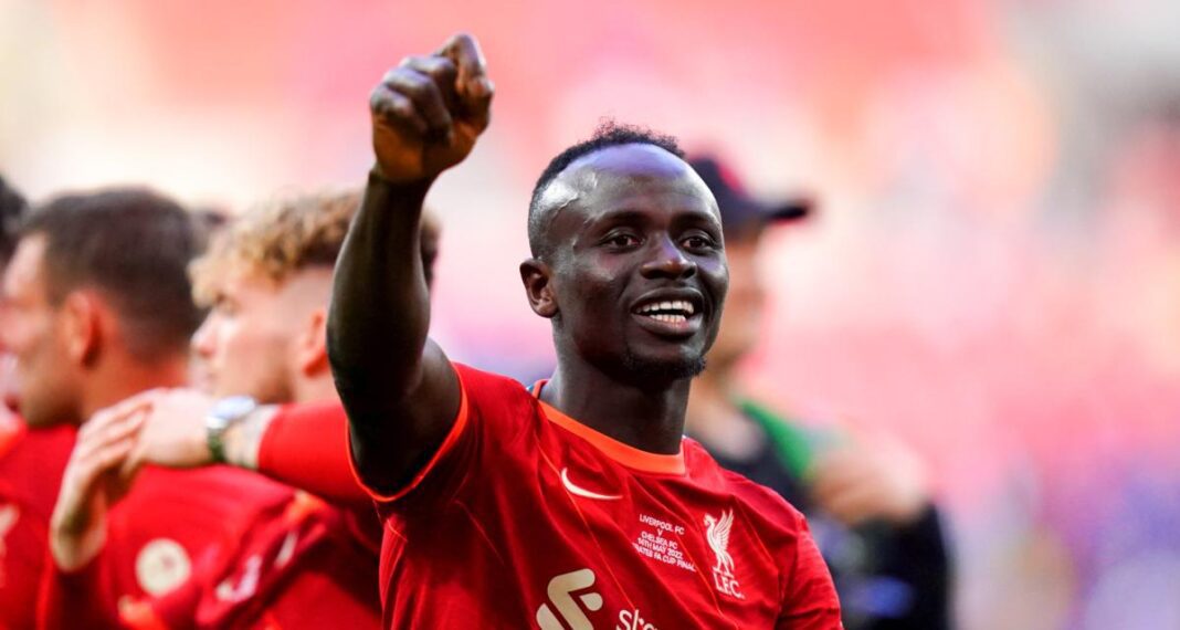 Sadio Mané en célébration Sadio Mané souriant en tenue de football rouge.