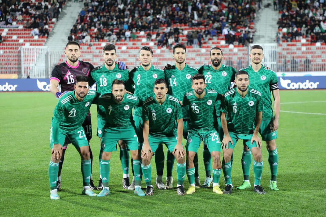 Groupe de joueurs de football algériens en uniforme vert sur le terrain.