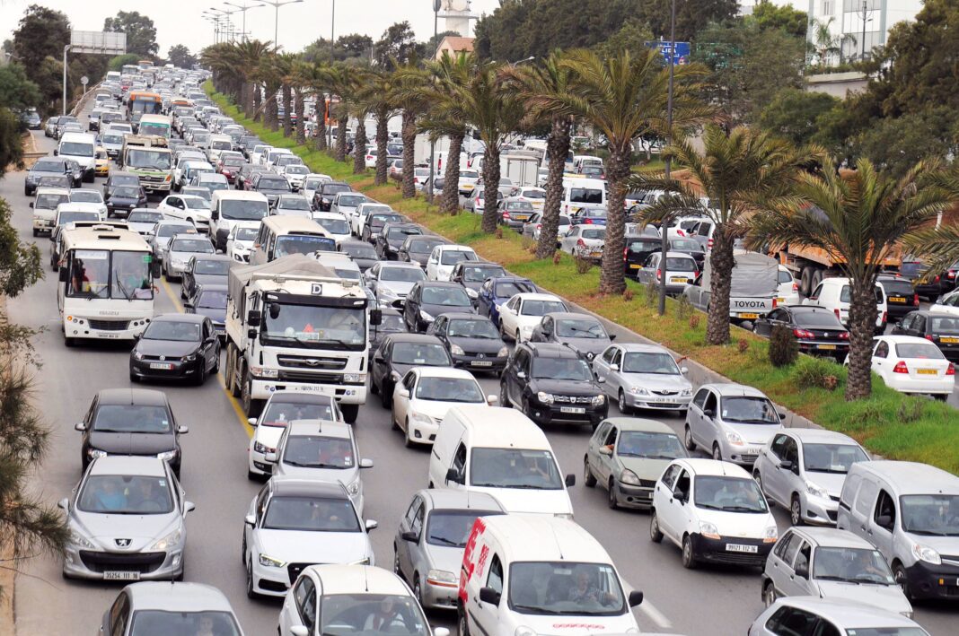 Trafic important sur une avenue bordée de palmiers en Algérie.