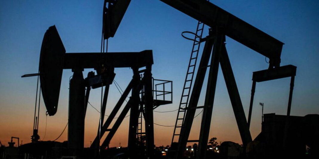 Pétrole et énergie au coucher du soleil Puits de pétrole en activité au coucher du soleil, silhouette sombre contre ciel coloré.