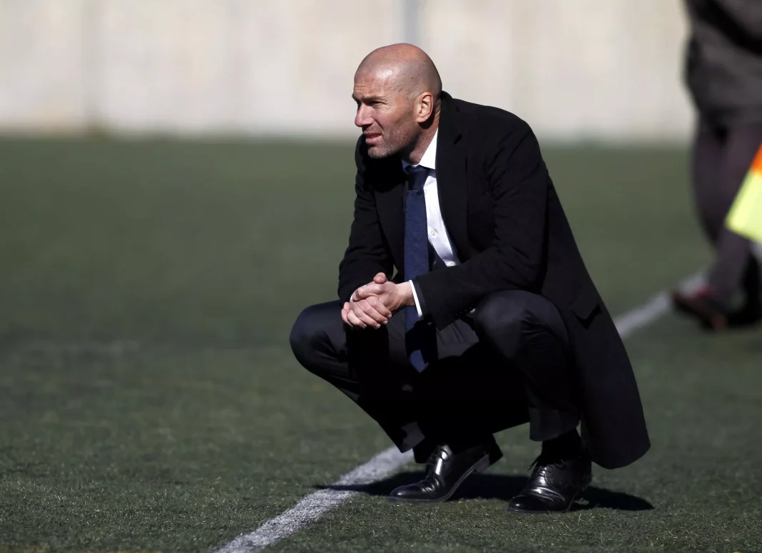 Zidane en pleine réflexion sur le terrain Zidane, entraîneur, en position de réflexion sur le terrain de football.