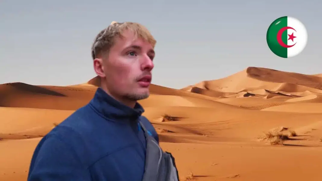 Algérie : Découvrez l’expérience surprenante d’un touriste français (Vidéo) Homme regardant le désert avec drapeau algérien en arrière-plan.