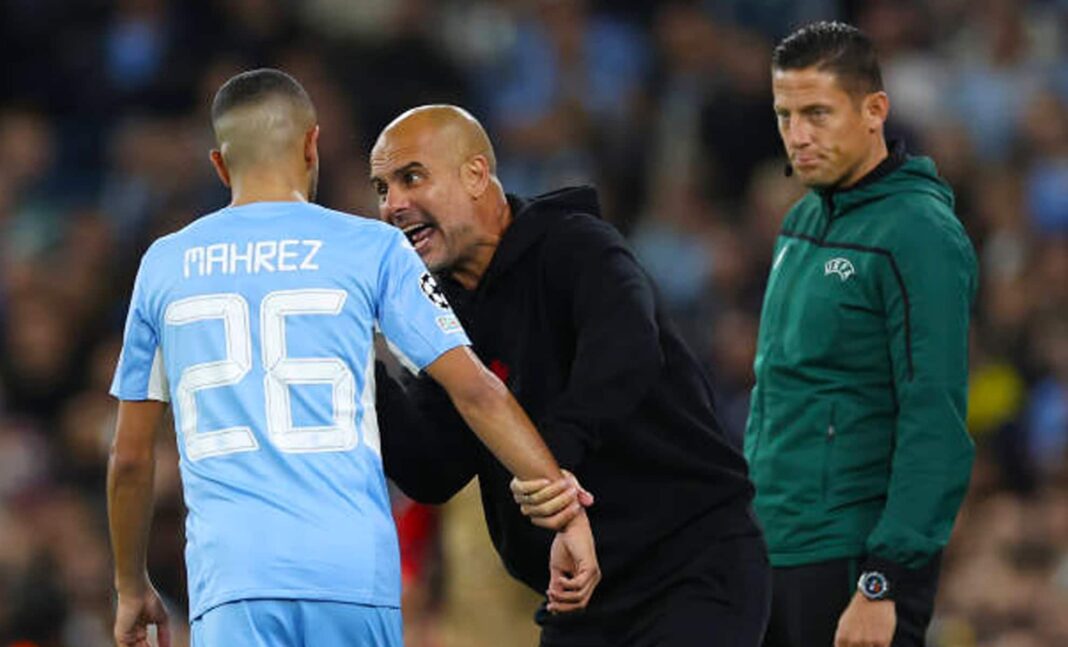 Mahrez en conversation avec l'entraîneur Guardiola lors d'un match de football.