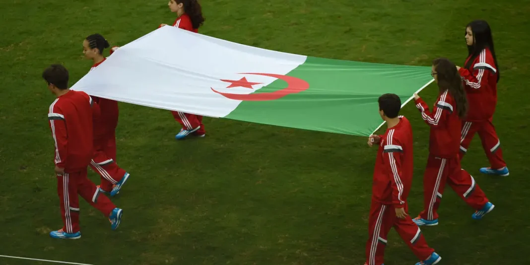 Jeunes handballeurs algériens en parade Jeunes sportifs algériens portant un drapeau national lors d'une cérémonie.