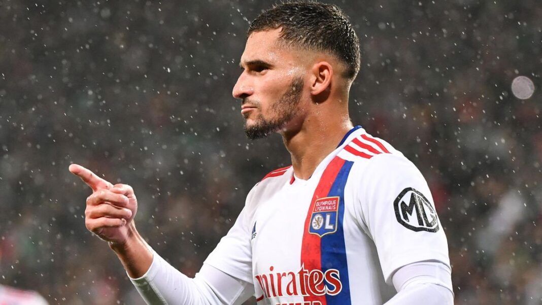 Houssem Aouar en action avec le maillot de l'OL sous la pluie.