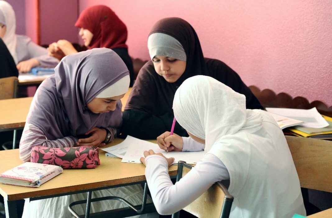 Port du « abaya » : entre autorités et dignitaires musulmans, ça tire à balles réelles. Jeunes femmes musulmanes en classe, portant des hijabs, concentrées sur leurs devoirs.