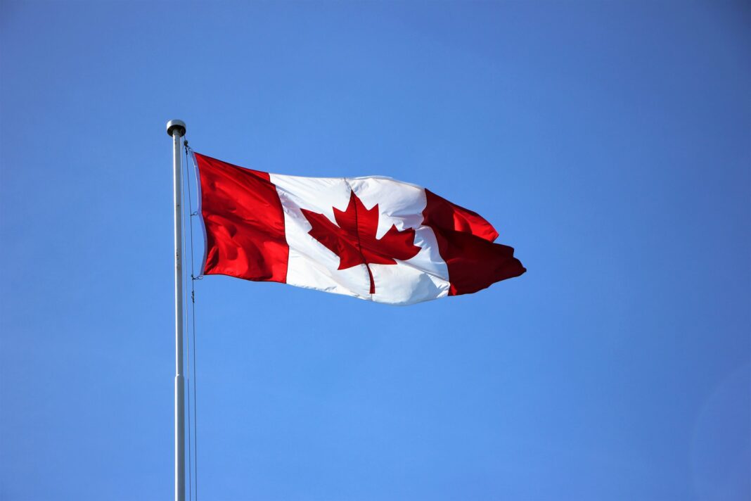 Drapeau du Canada flottant dans le ciel bleu clair.