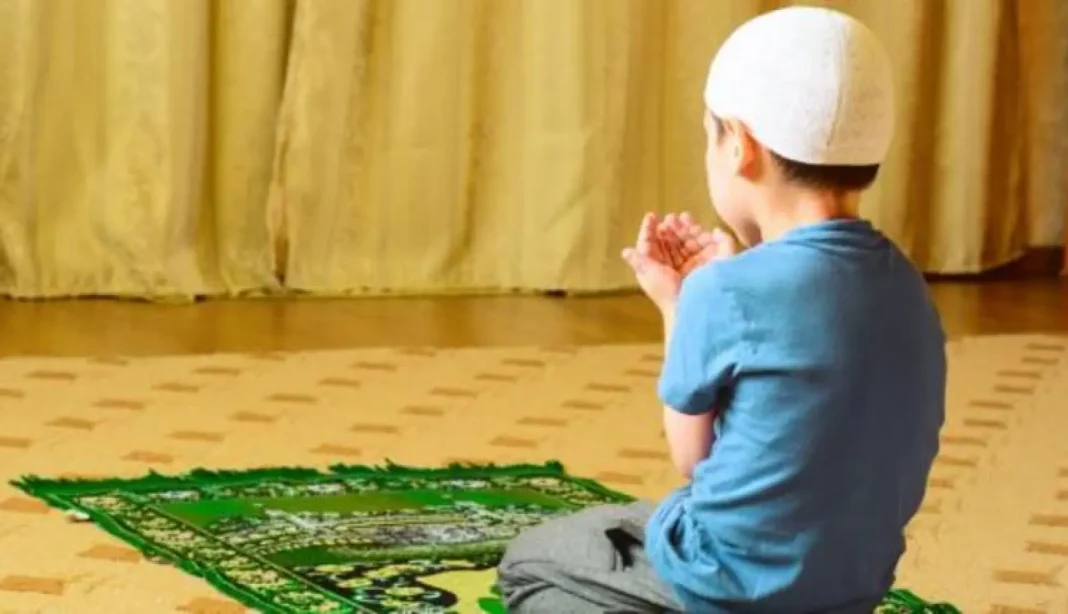 La prière dans les écoles irrite les Français Jeune garçon en prière dans une salle d'école avec tapis de prière.