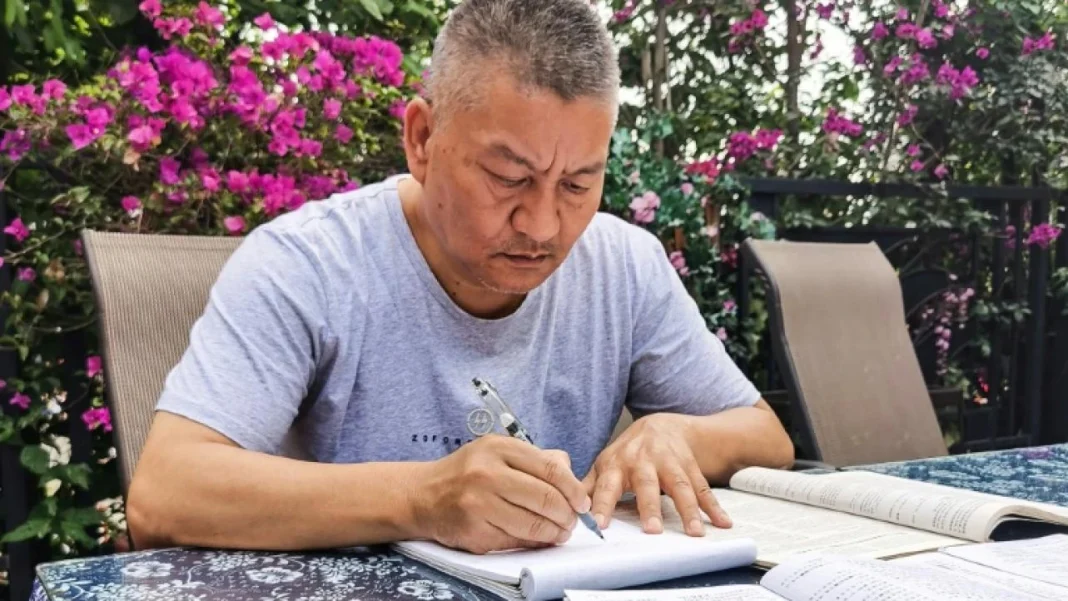 Chine : un millionnaire Algérien de 56 ans passe le bac pour la 27e fois Homme concentré en train d'écrire lors d'un examen en plein air.