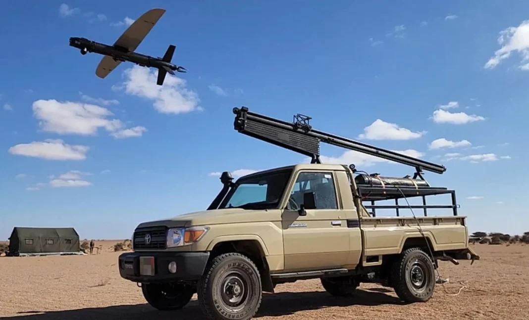 Véhicule militaire avec drone en vol Véhicule militaire dans le désert avec drone en vol dans le ciel bleu.