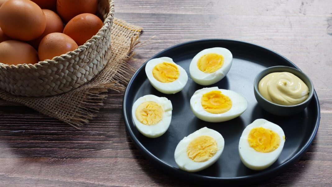 Ces 4 choses vont changer dans votre vie si vous manger des oeufs tous les jours Œufs durs coupés en moitiés avec sauce dans une assiette noire.