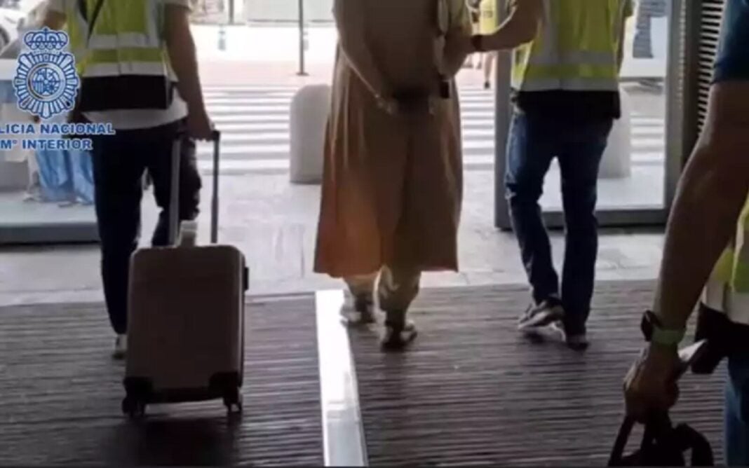 Espagne : une Marocaine abandonne son enfant dans un aéroport (Quel genre de mère ?) Personne en hijab avec valise à l'aéroport, entourée de personnel de sécurité.