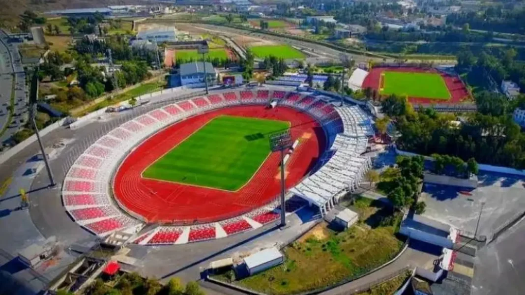 Algérie : la construction d’un nouveau stade aux normes mondiales annoncée Stade de football avec piste d'athlétisme et tribunes modernes.