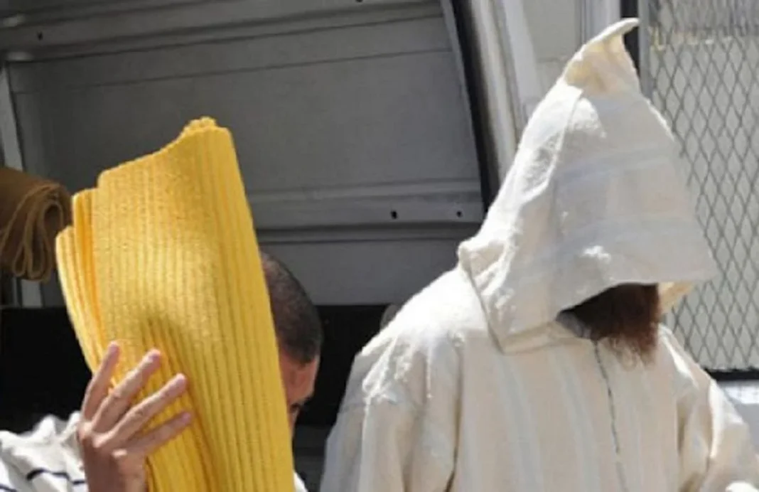 Imam marocain en prison, escorté par des agents de sécurité.