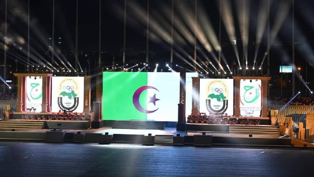 Scène principale avec drapeau algérien et symboles des Jeux Arabes 2023.