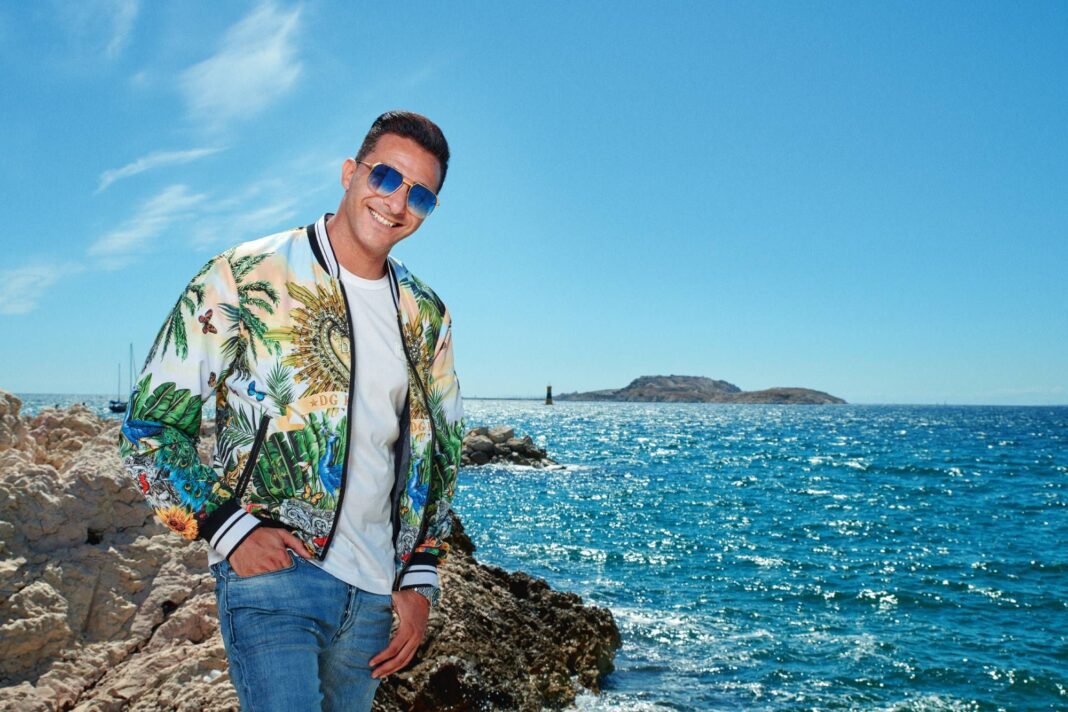 Algérie : voici la date du concert de l’Algérino à la coupole d’Alger Homme souriant en tenue décontractée près de la mer ensoleillée.