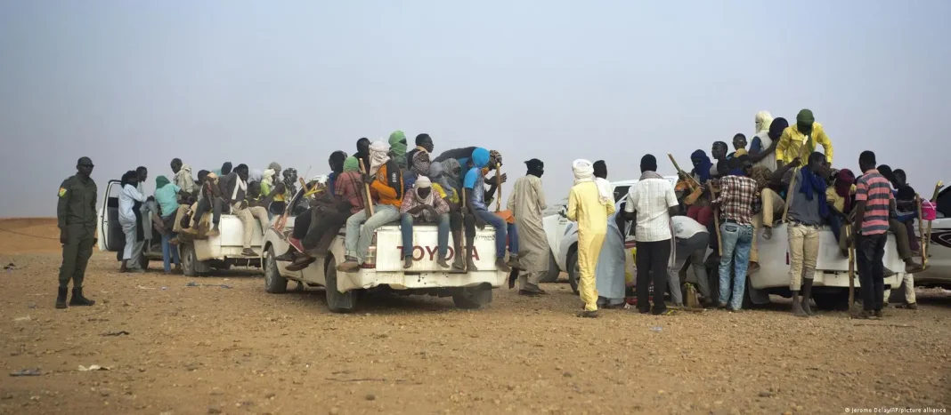 Migrants entassés dans des véhicules en déplacement dans un désert.