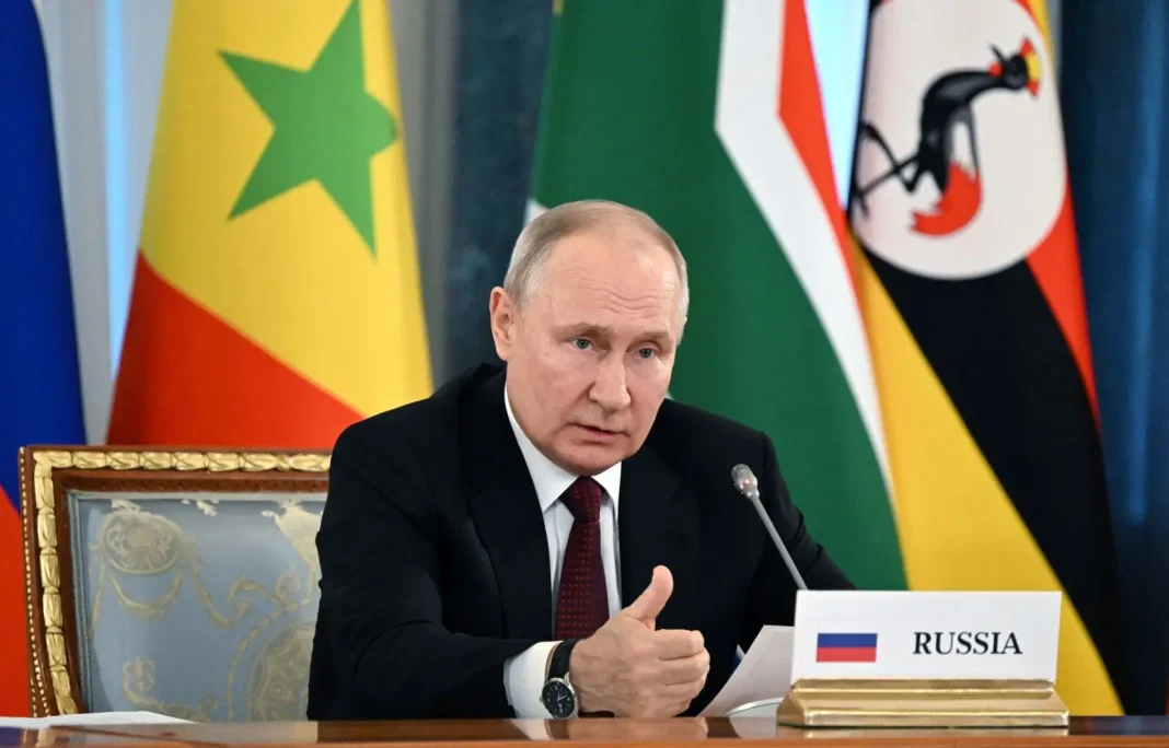Poutine souhaite, que l’Union africaine rejoigne le G20 Vladimir Poutine à une réunion avec drapeaux africains en arrière-plan.