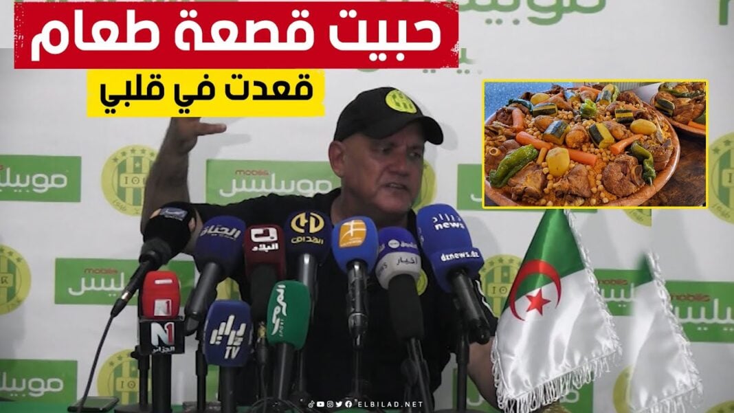 Après le maintien de la JSK en ligue 1 , l’entraîneur Bouzidi réclame du couscous à la viande Bouzidi lors d'une conférence avec plusieurs microphones et drapeau algérien.