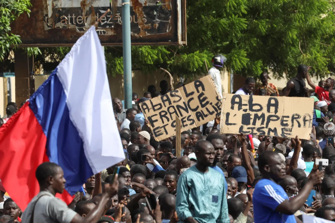 Manifestation au Niger avec drapeau français et pancartes.