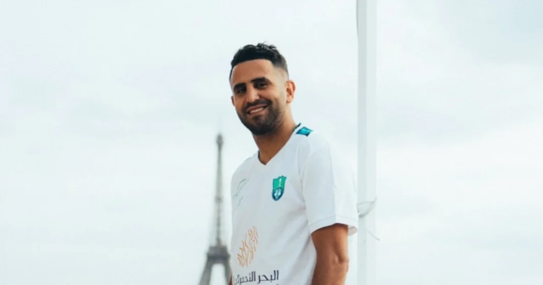 Mahrez souriant en maillot de football blanc.