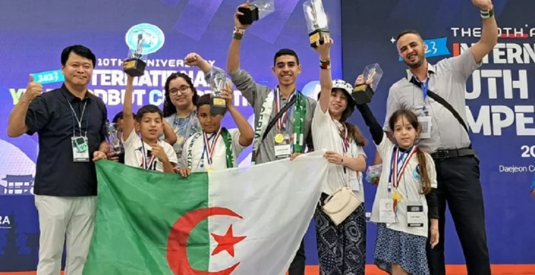 Algérie remporte un prix au concours de robotique Groupe d'enfants et d'adultes avec la drapeau algérien et des médailles.