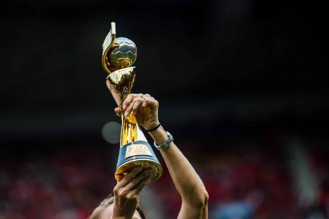 Main levant le trophée de la Coupe du Monde féminine.