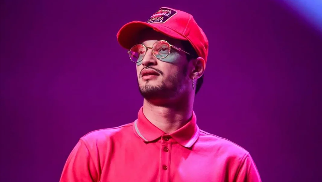 Soolking en performance musicale Soolking portant une casquette rouge et des lunettes sur scène.