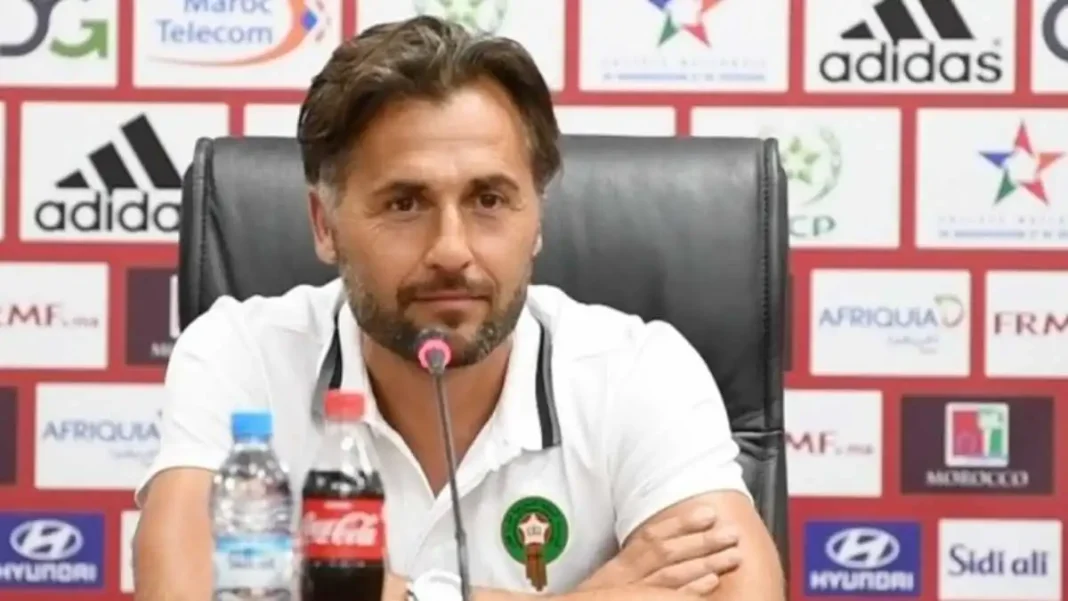 Beaumelle, contre l’arrivée de M’Bolhi au MC Alger Homme lors d'une conférence de presse avec logos sportifs en arrière-plan.