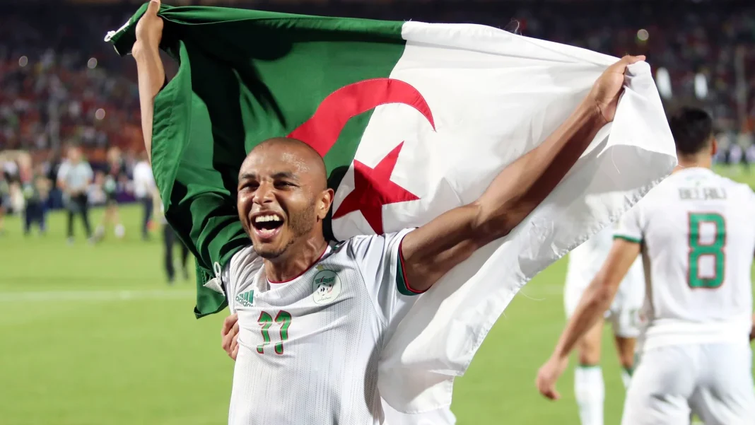 Yacine Brahimi en EN? L’étau se resserre de plus en plus Yacine Brahimi souriant avec le drapeau algérien lors d'un match.