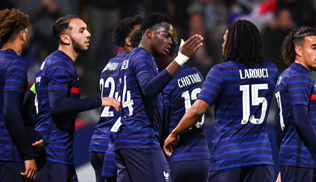 Équipe nationale de football algérienne Les joueurs algériens discutent lors d'un match, portant des maillots bleus avec noms et numéros.