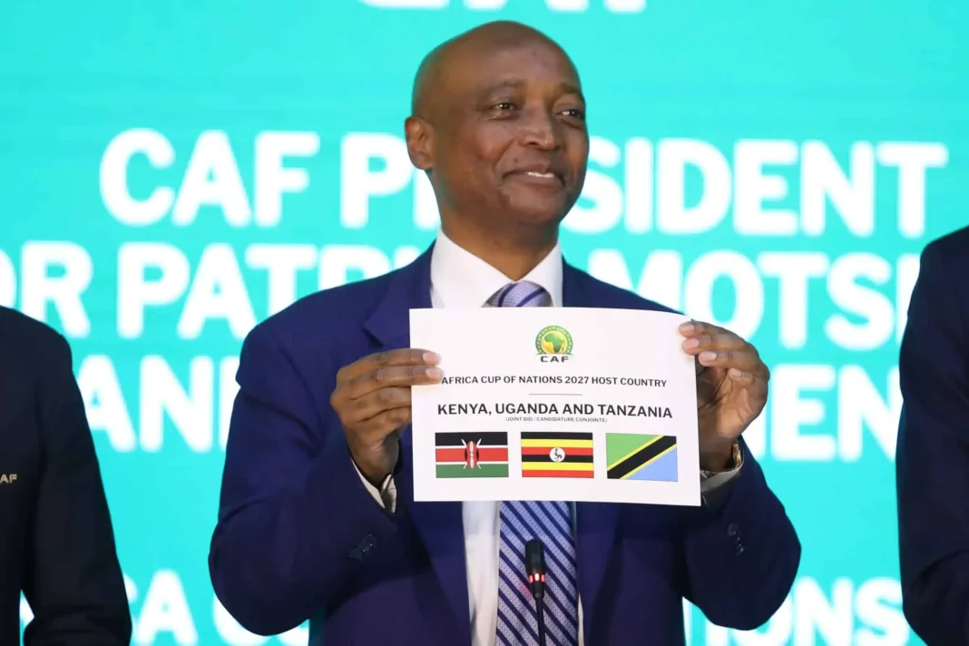 Patrice Motsepe tenant une affiche pour la CAN 2027 avec pays africains.