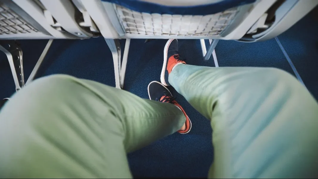Conseils pour voyager en avion Voyageur en avion avec chaussures retirées, assis en classe économique.