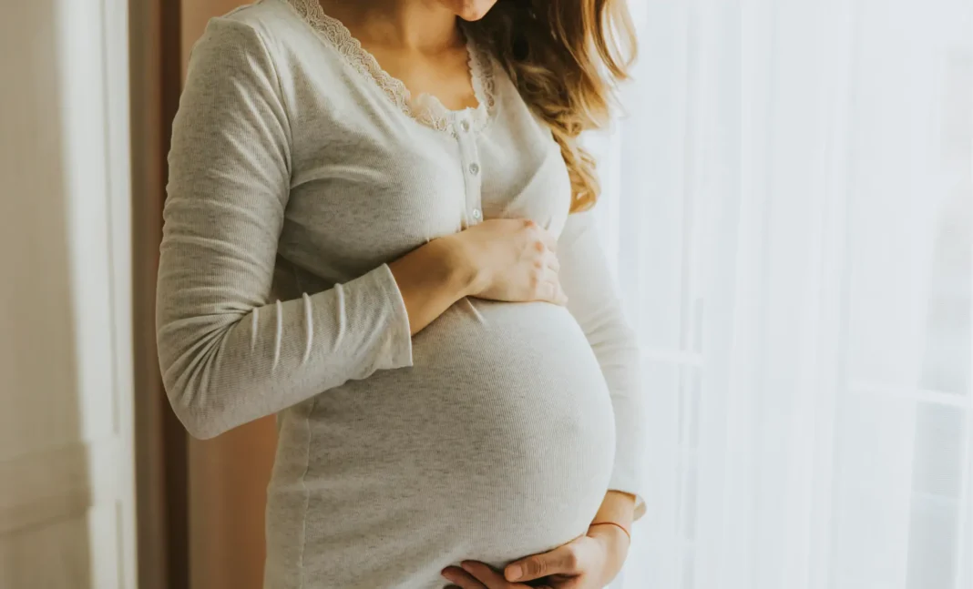 France : Algérien de 61 ans en garde à vue pour agression d’une femme enceinte Femme enceinte tenant son ventre devant une fenêtre lumineuse.