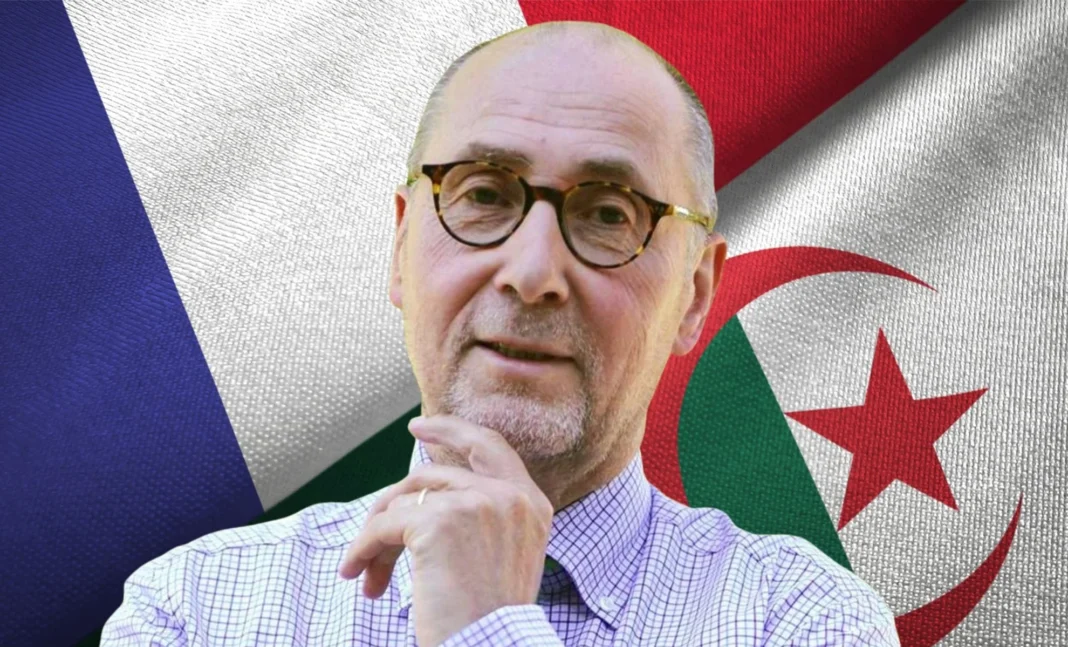 Homme avec lunettes devant drapeaux français et algérien.