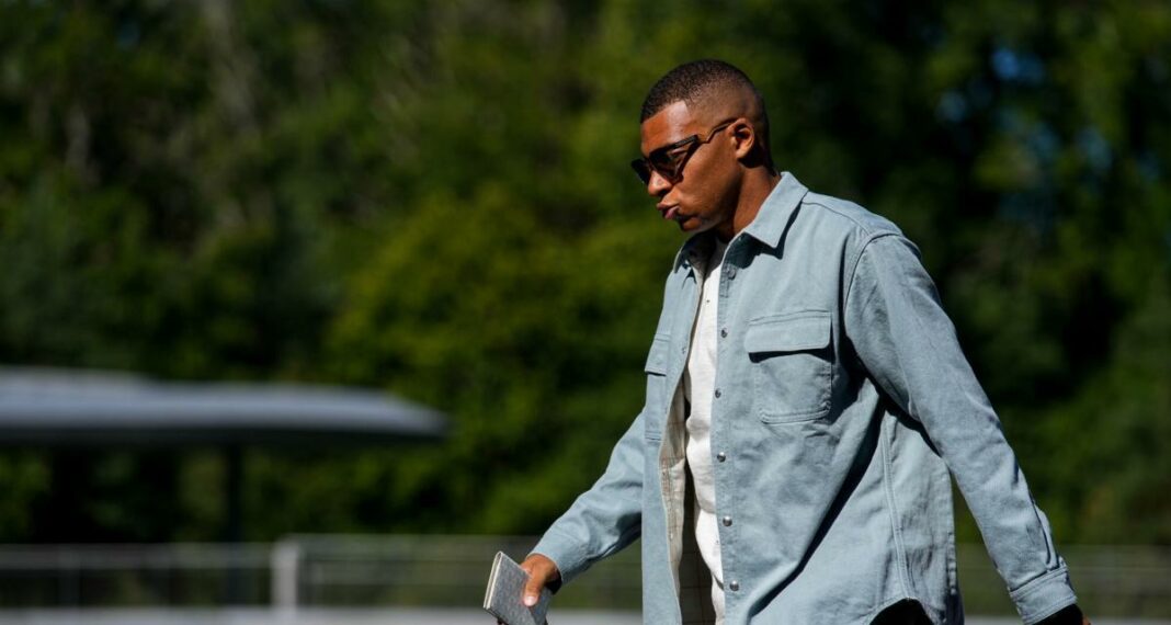 Kylian Mbappé, l’énorme coup de théâtre ! Jeune homme portant lunettes de soleil et chemise en extérieur.