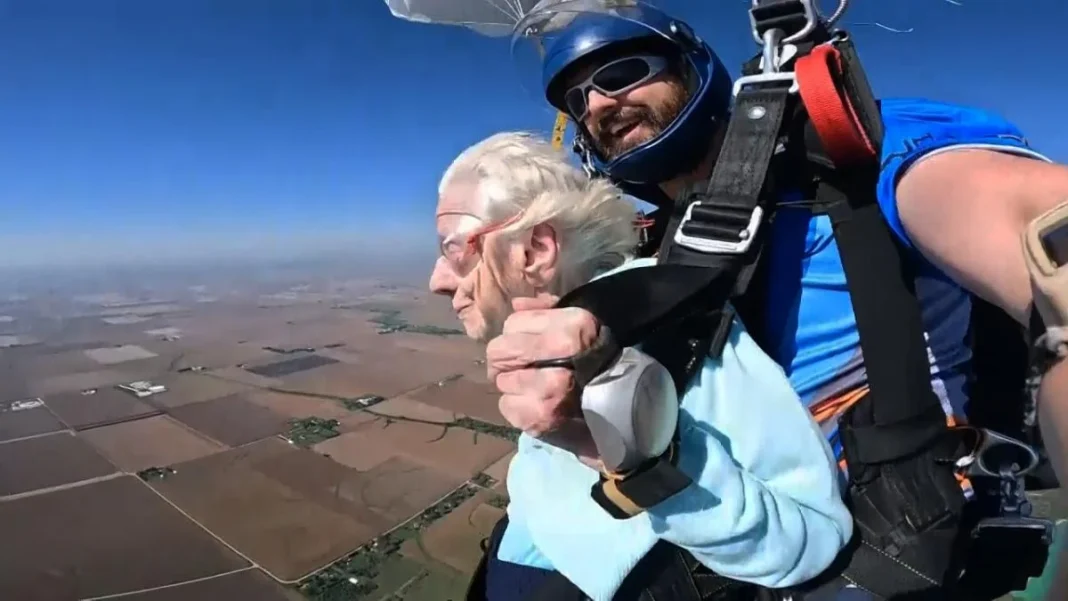 Prouesse ! A 104 ans, elle saute d’un avion à plus de 4.000 mètres d’altitude Femme âgée sautant en parachute avec un instructeur dans le ciel bleu.