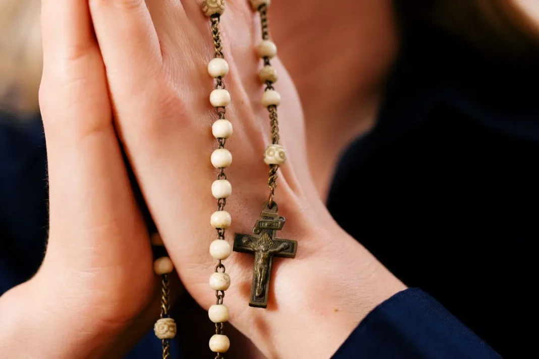 Préparation de la Journée Mondiale des Missions en Algérie : La prière du Rosaire au centre de l’élan spirituel Personne priant avec un chapelet lors d'une cérémonie religieuse.