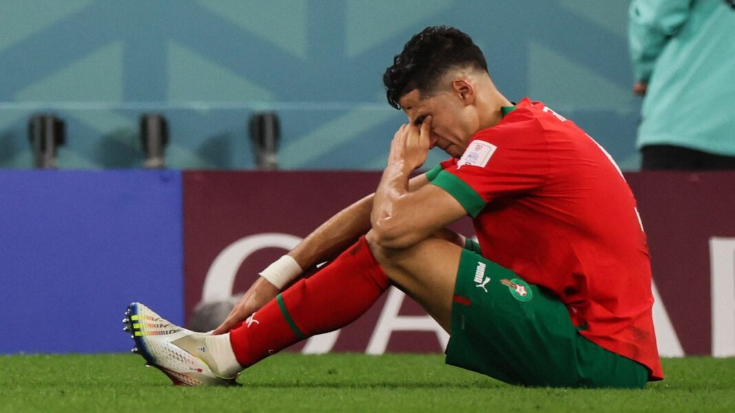 Le Maroc n’est pas favori pour la CAN 2023… Joueur marocain assis sur le terrain, visiblement déçu ou blessé.