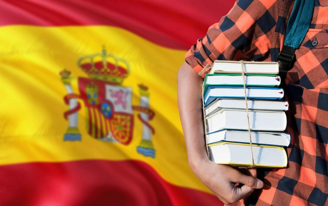 Erasmus-Bourses d’Études en Espagne pour les Algériens : Opportunité Internationale Étudiant avec livres et sac à dos devant le drapeau espagnol.
