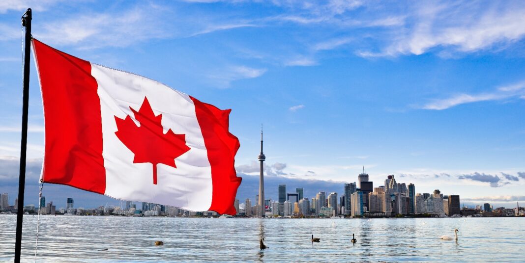 Le Canada facilite l’immigration pour les Marocains après le séisme de septembre Drapeau du Canada flottant avec la skyline de Toronto en arrière-plan.