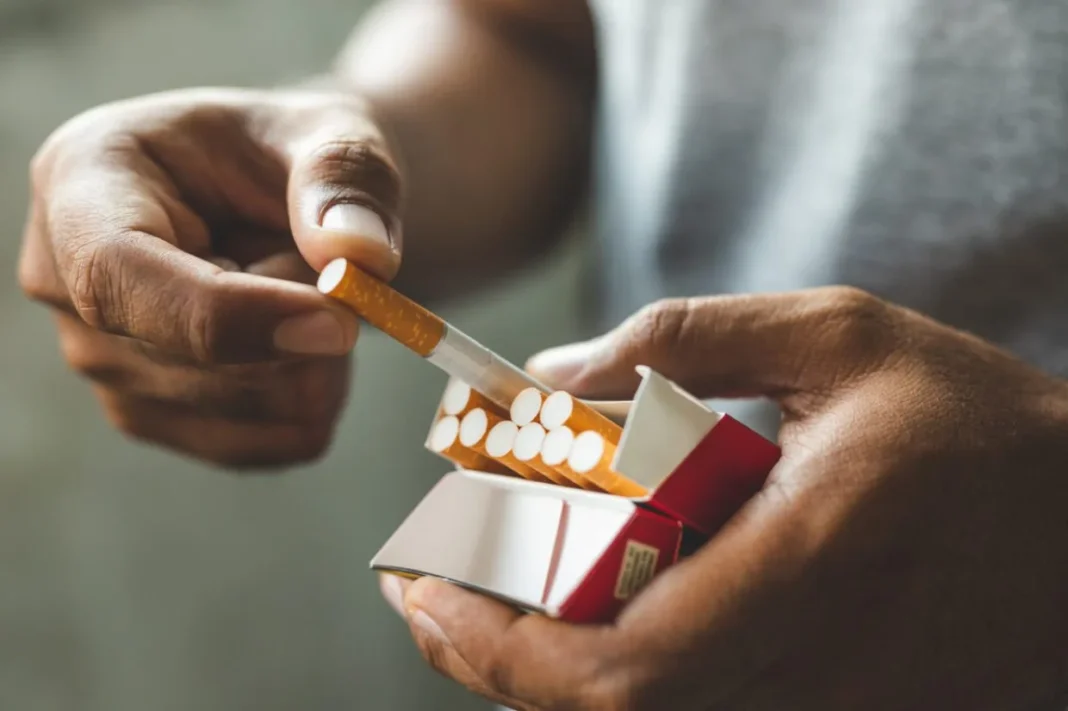 Augmentation des quotas de cigarettes pour les voyageurs : une bonne nouvelle pour les Algériens en Europe Main tenant une cigarette et une boîte d'allumettes.