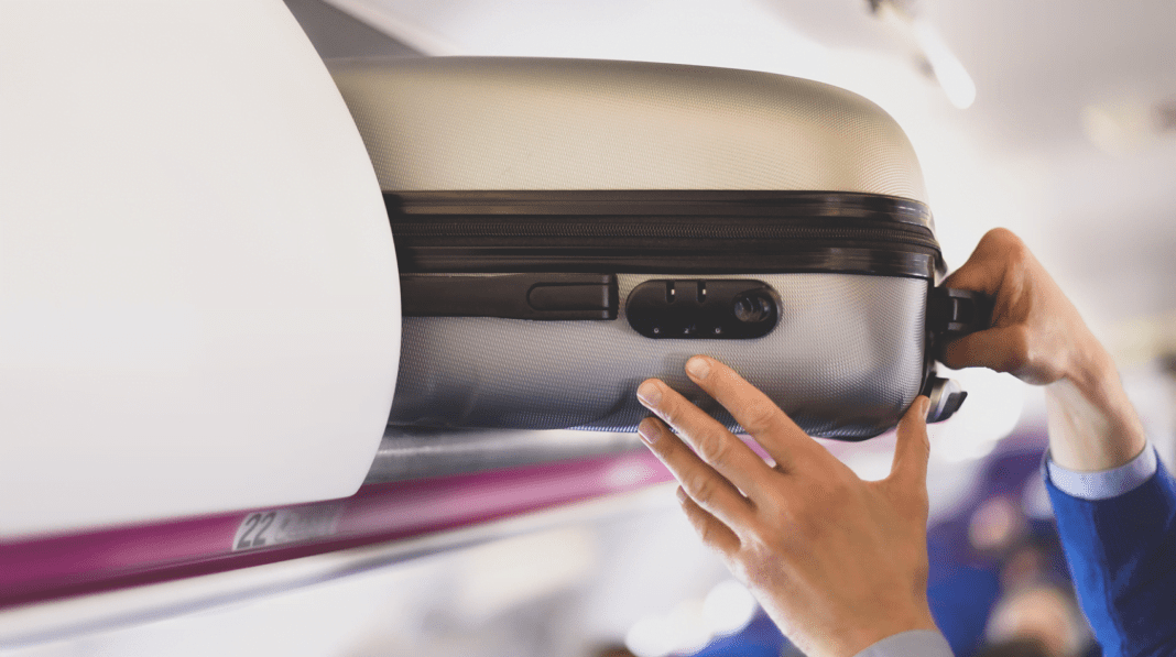 Fin des frais pour le bagage à main en cabine : Ce que vous devez Savoir Bagage cabine en avion prêt à être rangé dans le compartiment supérieur.