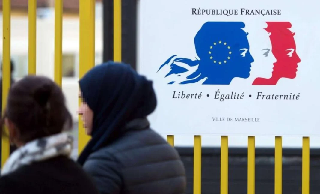 Affaire de Fraude : Un homme accusé d’avoir reconnu faussement la paternité de 17 enfants en France Deux femmes discutant devant un panneau de la République française.