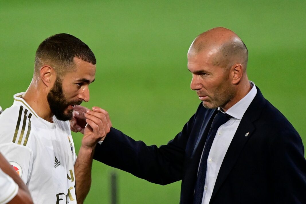Karim Benzema et Zinedine Zidane en conversation lors d'un match de football.
